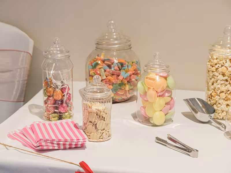 Candy bar con vitroleros de dulces, pinzas y bolsas para que los invitados se sirvan