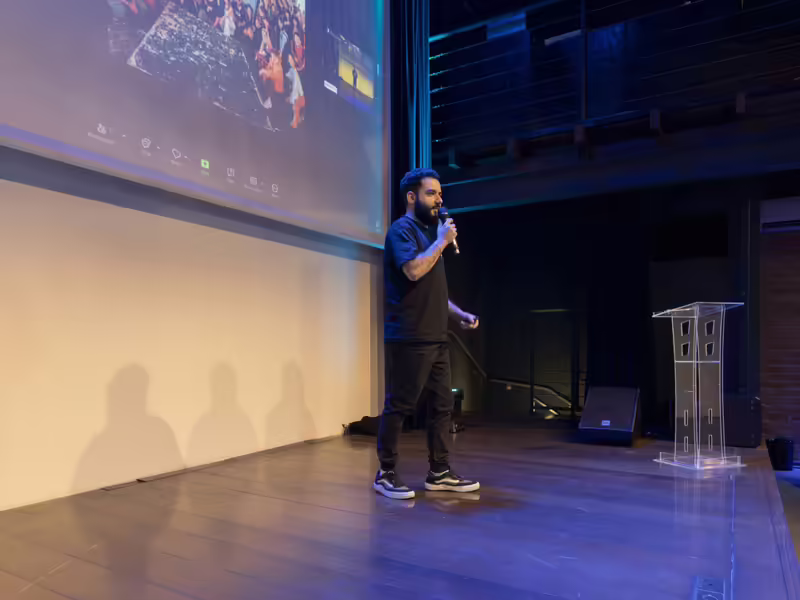 Ponente en un escenario corporativo con una pantalla LED detrás mostrando su presentación